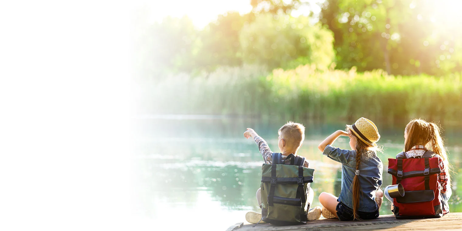 Gruppe von Kindern sitzen auf einem Holzsteg an einem Fluss