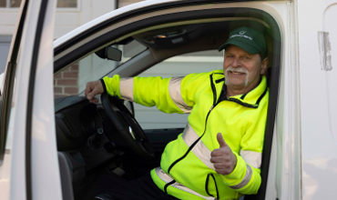Diversity Menu driver sits at the wheel of a delivery vehicle and shows a positive thumb sign with his hand.
